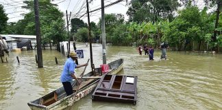 A man attempts to save a piece of furniture on a flooded road in Tabasco.