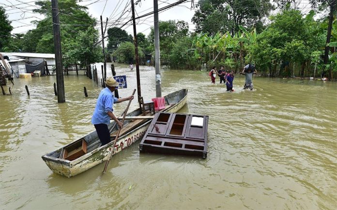 A man attempts to save a piece of furniture on a flooded road in Tabasco.
