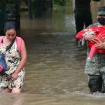 A soldier helps a woman and her child escape flooding in Tabasco.