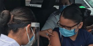 A healthcare worker administers a flu shot to a passenger in a car in Chihuahua.