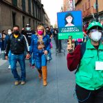 A Mexico City worker displays a sign urging the correct use of face masks.