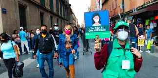 A Mexico City worker displays a sign urging the correct use of face masks.