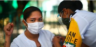 A healthcare worker raises her fist in defiance as she is injected with Covid vaccine in Mexico City.