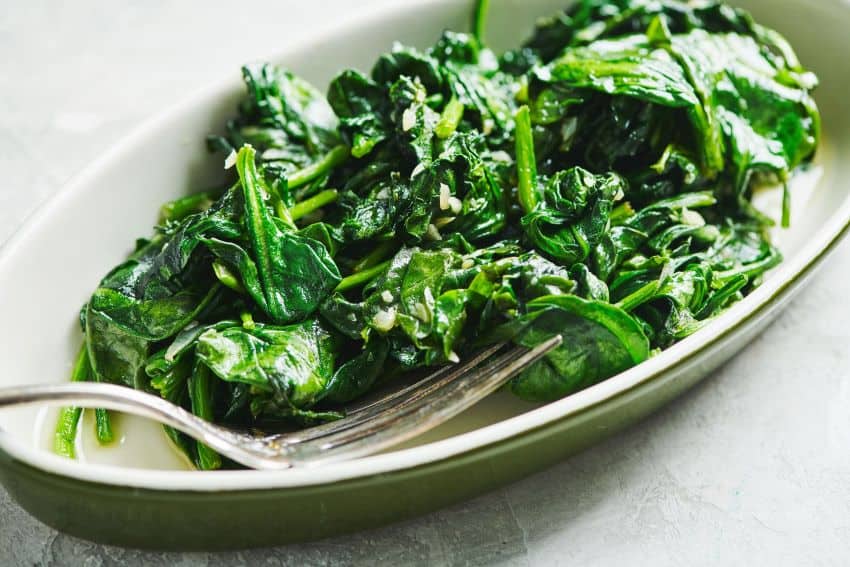 Carefully flip these spinach leaves to distribute the olive oil.