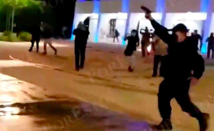 An officer fires his weapon during a protest last year in Cancún. 