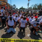 Migrants in Tijuana kneel at the border