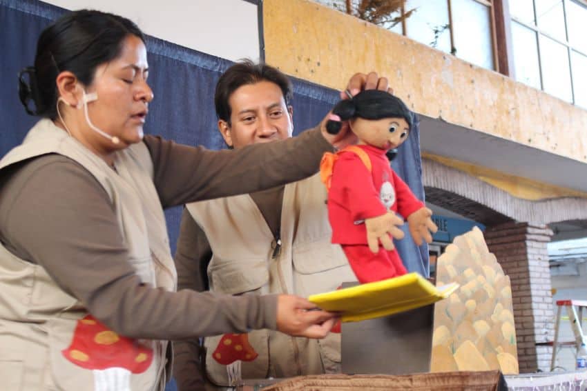 Reyes and Ledesma on stage with a puppet. The two do not hide themselves during performances, but Reyes says that they “melt” into the background.
