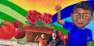 Artist Julia Celeste with budding painter Edgar in front of a mural in the Las Misiones neighborhood of San Quintín, depicting principal crops of the Valley.