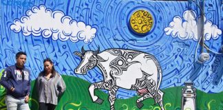 Iván Galeazzi Cahuantzi and Zuri Merlo with one of the murals they're together bringing to life in the town of Chipilo, Puebla to illustrate aspects of its history.