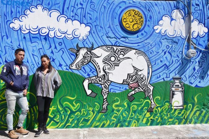 Iván Galeazzi Cahuantzi and Zuri Merlo with one of the murals they're together bringing to life in the town of Chipilo, Puebla to illustrate aspects of its history.