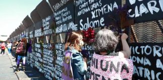 Women in Mexico City writing femicide victims' names onto metal barriers authorities had installed in anticipation of International Women's Day.