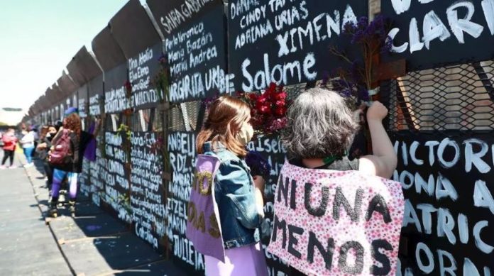 Women in Mexico City writing femicide victims' names onto metal barriers authorities had installed in anticipation of International Women's Day.