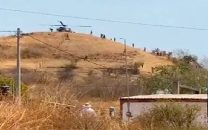 An army helicopter delivers supplies to soldiers camped outside the city of Aguililla.