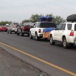 A convoy of vehicles is escorted by police to provide security.