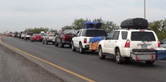 A convoy of vehicles is escorted by police to provide security.