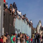 Migrants at the Mexico-US border wall.