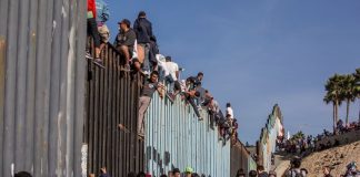 Migrants at the Mexico-US border wall.