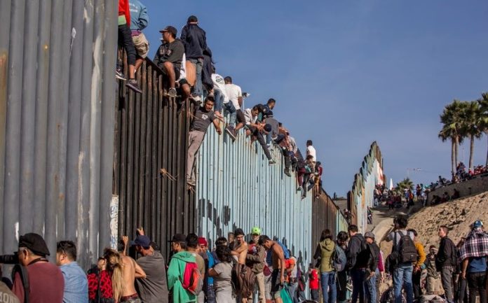 Migrants at the Mexico-US border wall.
