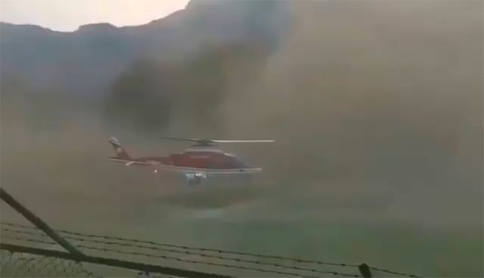 The helicopter amid a huge cloud of dust.