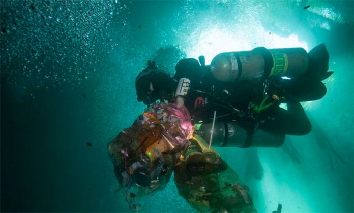 A diver with bags of waste recovered from a cenote.