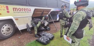 Soldiers remove meth from the cargo bay of a bus bearing the Morena logo.