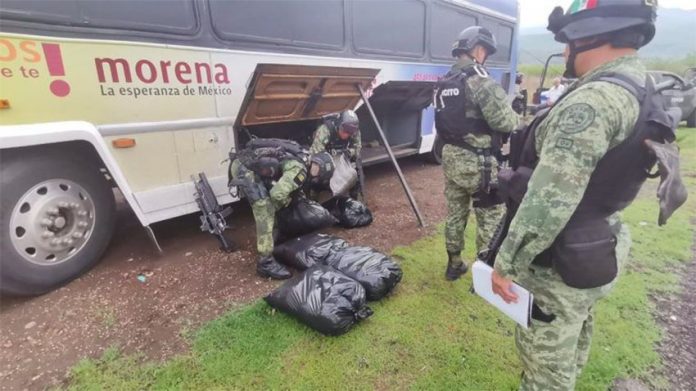 Soldiers remove meth from the cargo bay of a bus bearing the Morena logo.