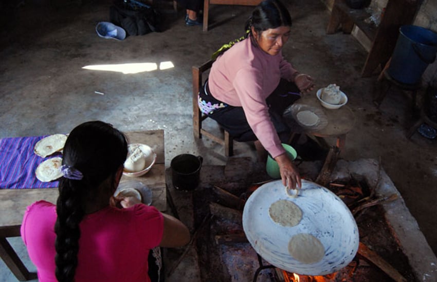 Women make tortillas in a rustic home in Amaquil.