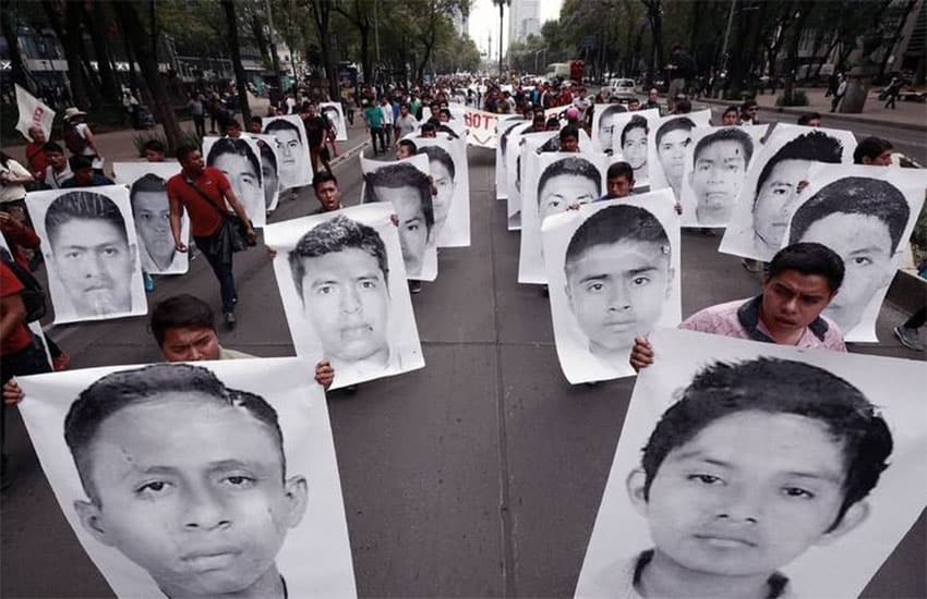 Protesters carry signs showing the faces of the disappeared Ayotzinapa students