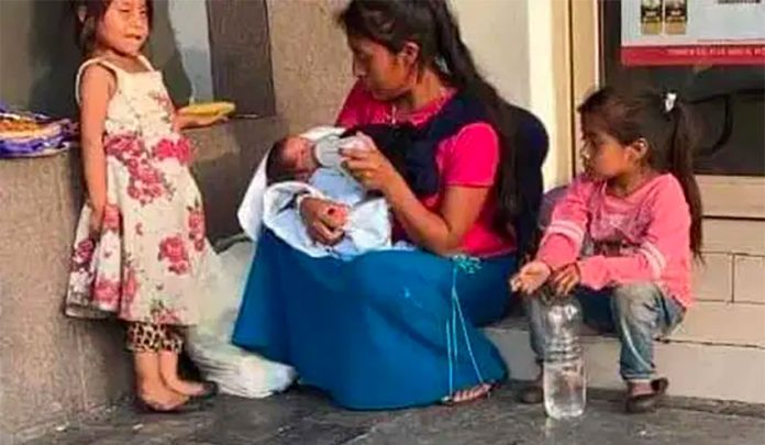 The young mother feeds the baby that was left in her care in downtown Monterrery.