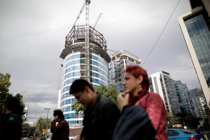 People walk by a building under construction in Mexico City