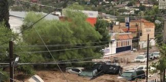 Vehicles are swept away by a river of water on a Nogales street Tuesday.