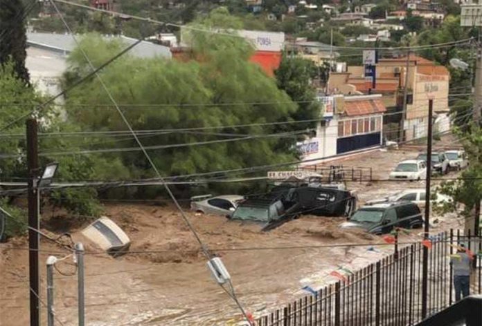 Vehicles are swept away by a river of water on a Nogales street Tuesday.