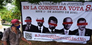 A man walks by a sign encouraging participation in the August referendum on ex-presidents.