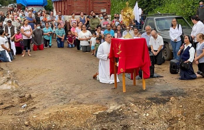 Rev. José Luis Martínez Chávez leads mass next to the place where an armed group destroyed the road, blocking access into town.