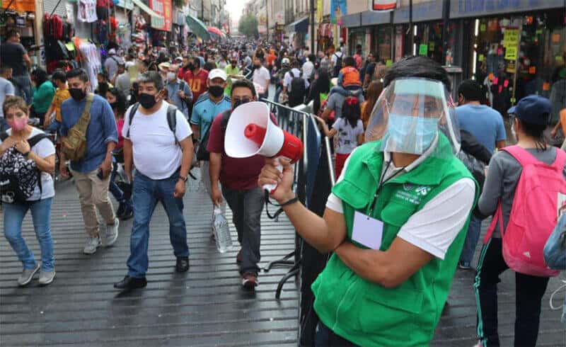 Crowds of masked pedestrians in the streets of Mexico City.