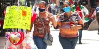 Women in Tabasco walk past a display of face masks.