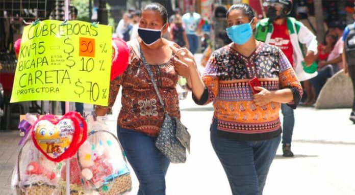 Women in Tabasco walk past a display of face masks.