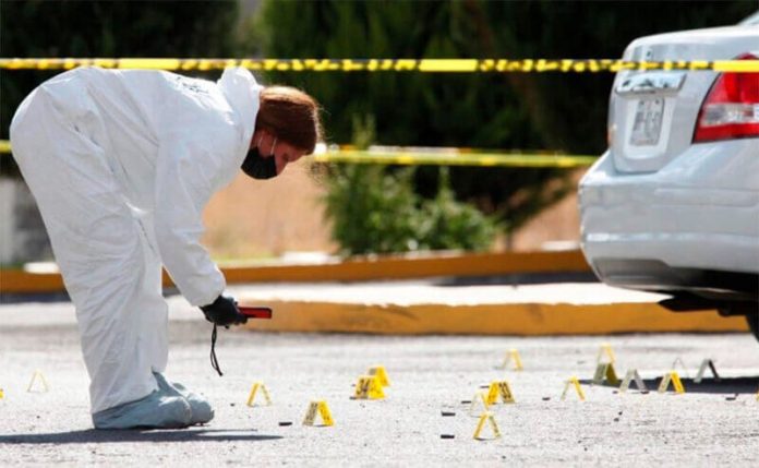 A forensic expert studies bullet casings at a Jalisco crime scene in 2020.