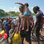 Migrants cross a shallow area of the Rio Grande