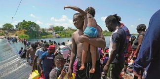 Migrants cross a shallow area of the Rio Grande
