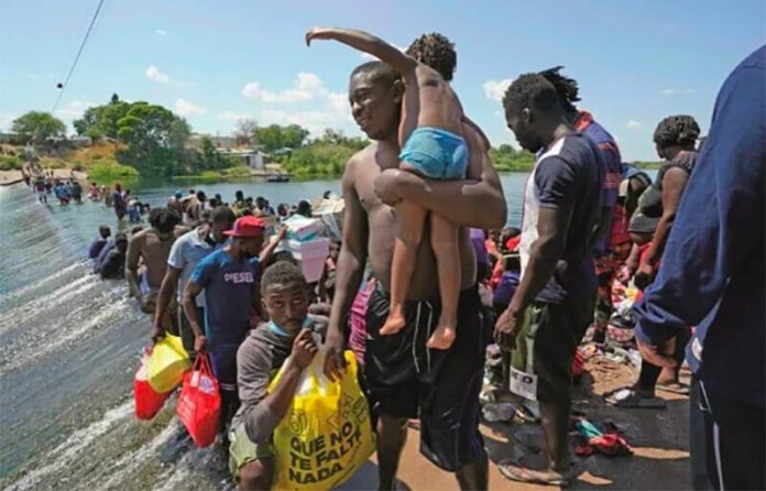 Migrants cross a shallow area of the Rio Grande