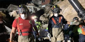 Searchers remove a body from the rubble.