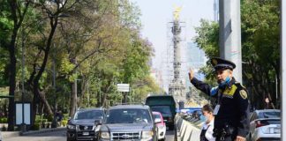 A transit police officer directs traffic at a Mexico City crosswalk.