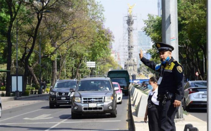 A transit police officer directs traffic at a Mexico City crosswalk.