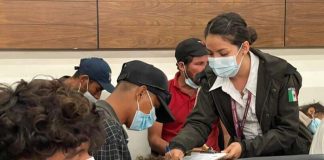 INM official helps migrants fill out paperwork