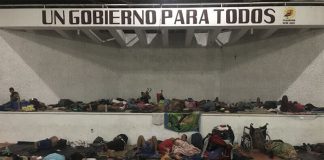 Migrants sleep under a sign that says 'A Government for Everyone,' in Chiapas.