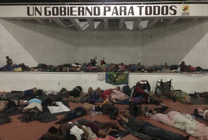 Migrants sleep under a sign that says 'A Government for Everyone,' in Chiapas.