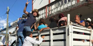 Migrants climb aboard a truck to hitch a ride.
