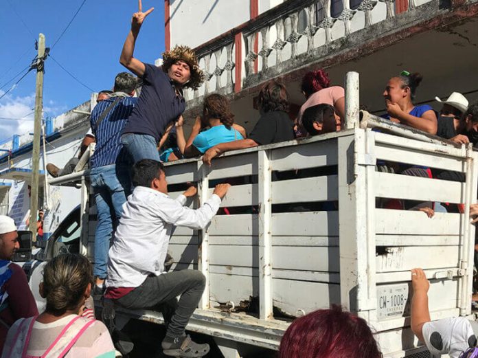 Migrants climb aboard a truck to hitch a ride.