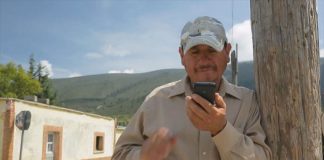 A man in a rural area checks his cell phone.